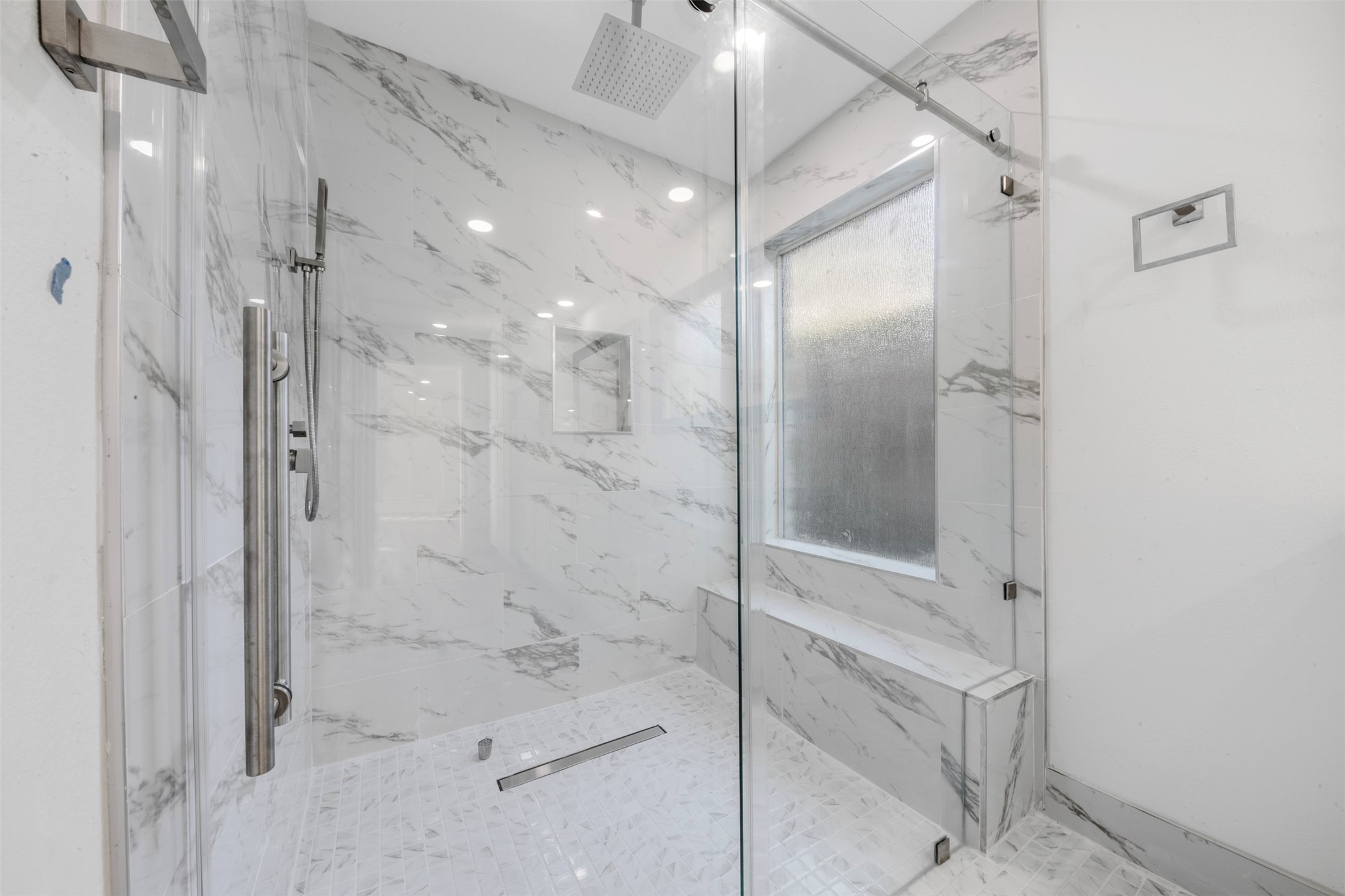 9543 Enstone Circle Spring, TX 77379 - Photo 21 of 50 This bathroom features a spacious, modern shower with sleek glass doors, marble-style tiling, a built-in bench, and a large rainfall showerhead.