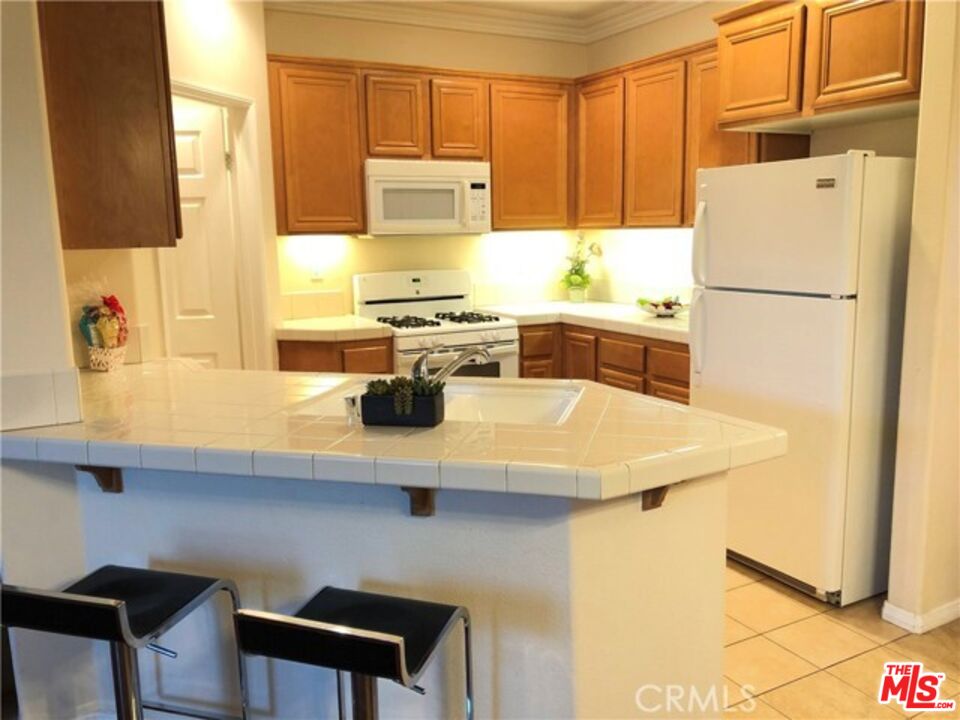 9497 Jack Rabbit Drive, Unit 106 Rancho Cucamonga, CA 91730 - Photo 4 of 14 a kitchen with a refrigerator a stove a sink and a counter