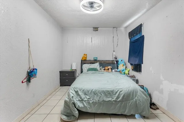 a bedroom with a bed a dresser and potted plant