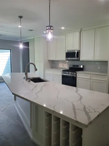 a kitchen with kitchen island granite countertop a sink a counter top space appliances and cabinets