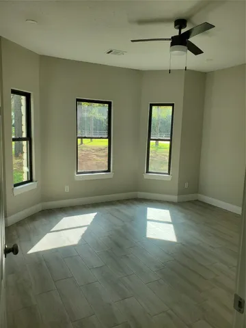 an empty room with windows and ceiling fan
