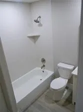 a white toilet sitting next to a bath tub