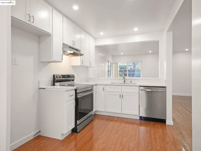 a kitchen with a white cabinets and wooden floor