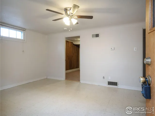 an empty room with a chandelier fan and windows