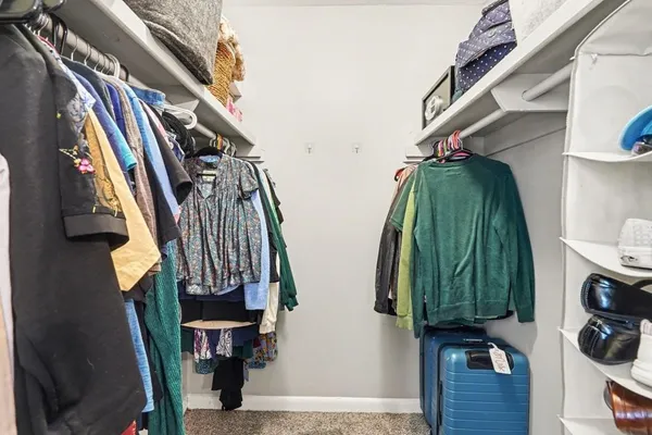 a view of walk in closet with clothes and shoes