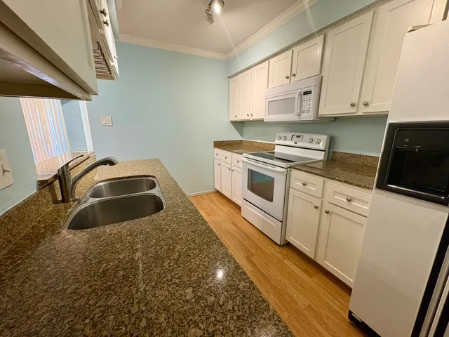 a kitchen with granite countertop a sink a stove and cabinets