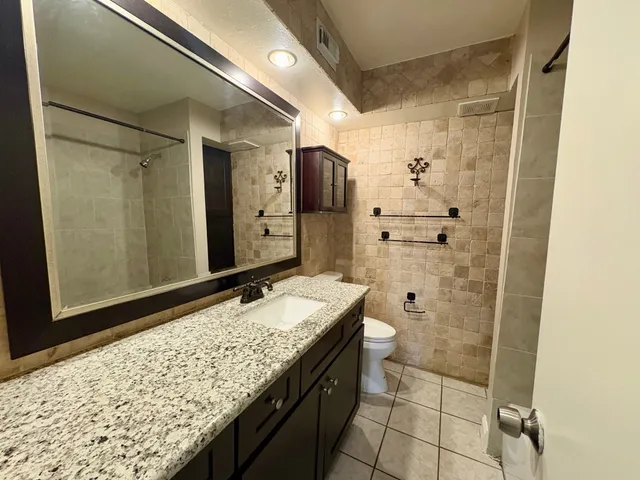 a bathroom with a granite countertop sink and a shower