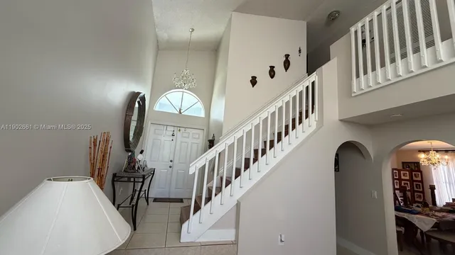 a view of staircase with railing and a chandelier