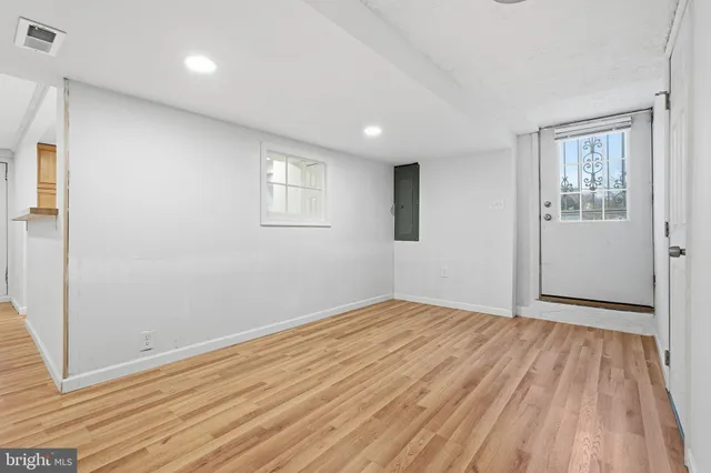 an empty room with wooden floor and windows