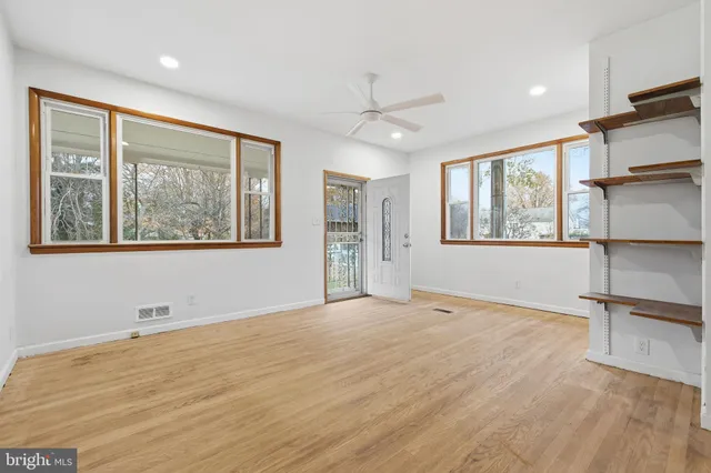 a view of an empty room with a window and wooden floor
