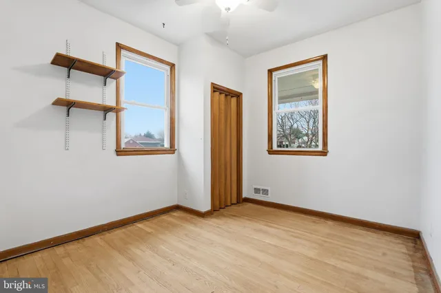 a view of empty room with wooden floor and fan