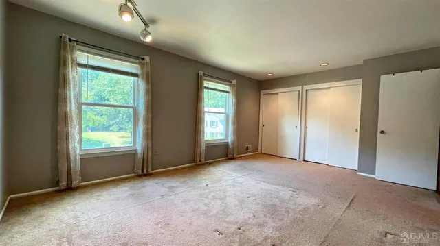 a view of an empty room with window and closet area