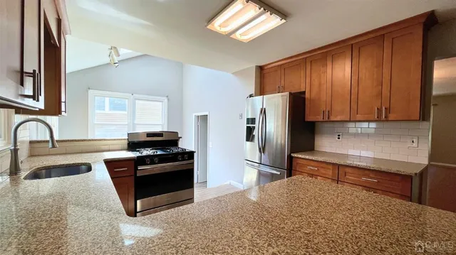 a kitchen with stainless steel appliances granite countertop a refrigerator and a sink