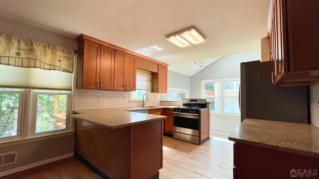 a kitchen with stainless steel appliances granite countertop a stove a sink and a refrigerator