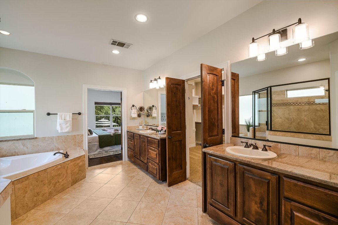 524 Highland Spring Lane Georgetown, TX 78633 - Photo 15 of 39 a spacious bathroom with a granite countertop sink a mirror a shower and bathtub