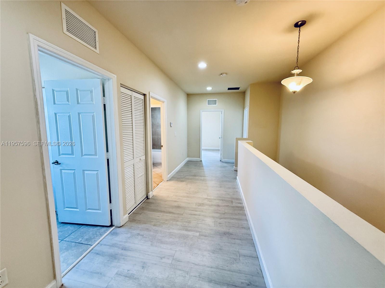 3385 West 86th Terrace, Unit 3385 Hialeah, FL 33018 - Photo 14 of 19 a view of a hallway with wooden floor and a chandelier