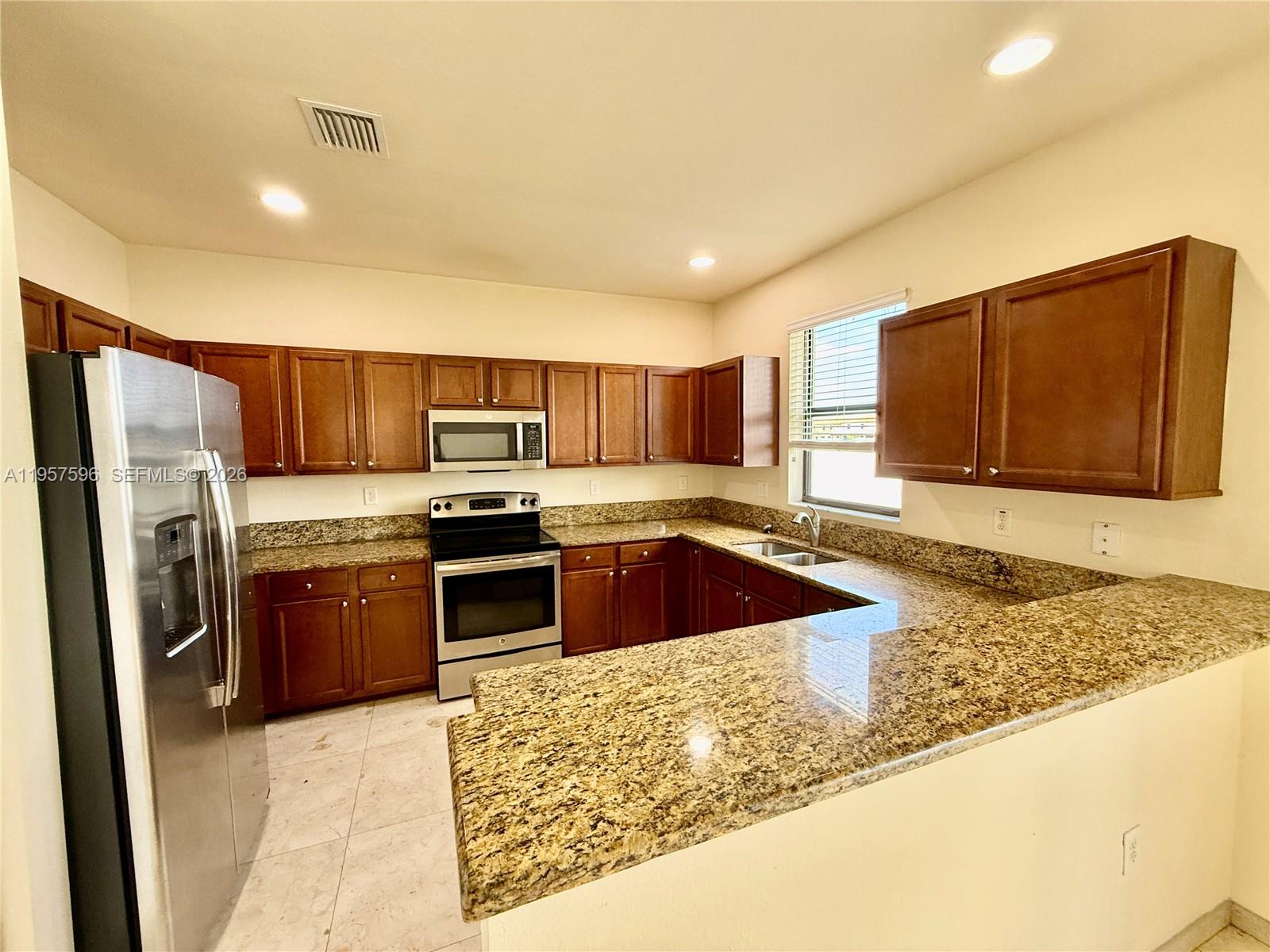 3385 West 86th Terrace, Unit 3385 Hialeah, FL 33018 - Photo 9 of 19 a kitchen with stainless steel appliances granite countertop a refrigerator a stove top oven and a sink with wooden floor