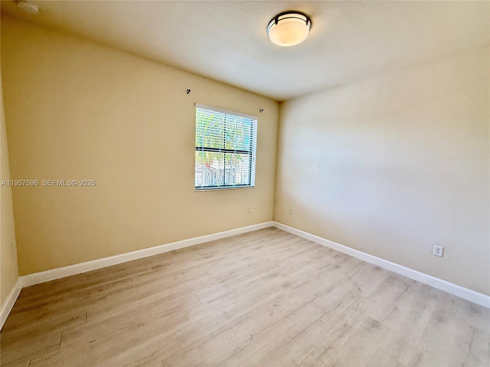 3385 West 86th Terrace, Unit 3385 Hialeah, FL 33018 - Photo 10 of 19 an empty room with wooden floor and windows