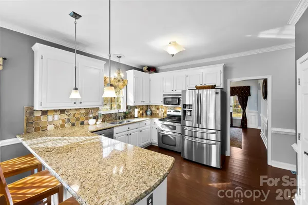 a kitchen with stainless steel appliances granite countertop a refrigerator a sink and a stove