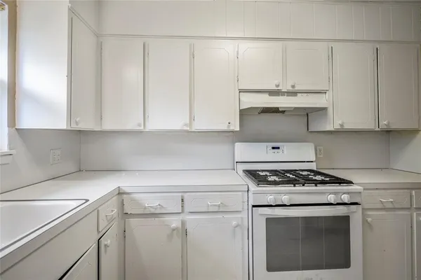 a kitchen with white cabinets and appliances