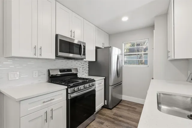 a kitchen with stainless steel appliances white cabinets a stove a microwave and a refrigerator