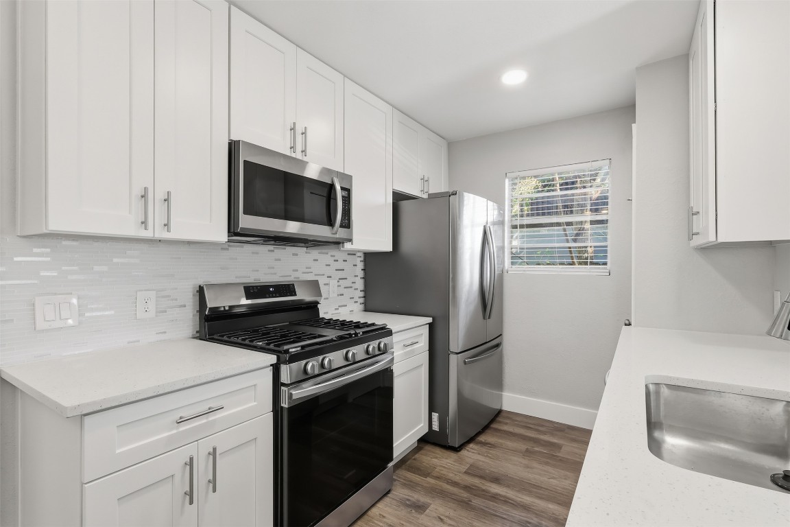 a kitchen with stainless steel appliances white cabinets a stove a microwave and a refrigerator