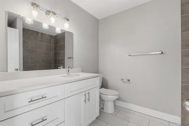 a bathroom with a granite countertop sink a toilet and shower