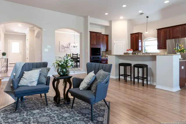 a living room with furniture kitchen view and a wooden floor