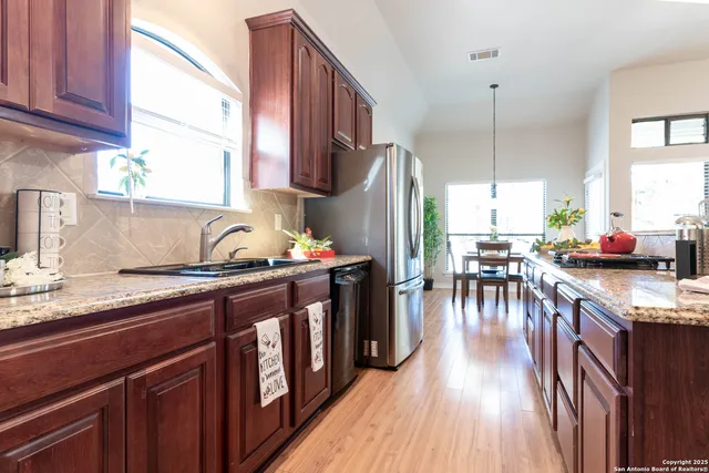 a kitchen with stainless steel appliances granite countertop a sink a stove and a wooden floors