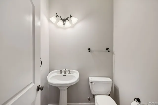 a view of a hallway with wooden floor and a bathroom