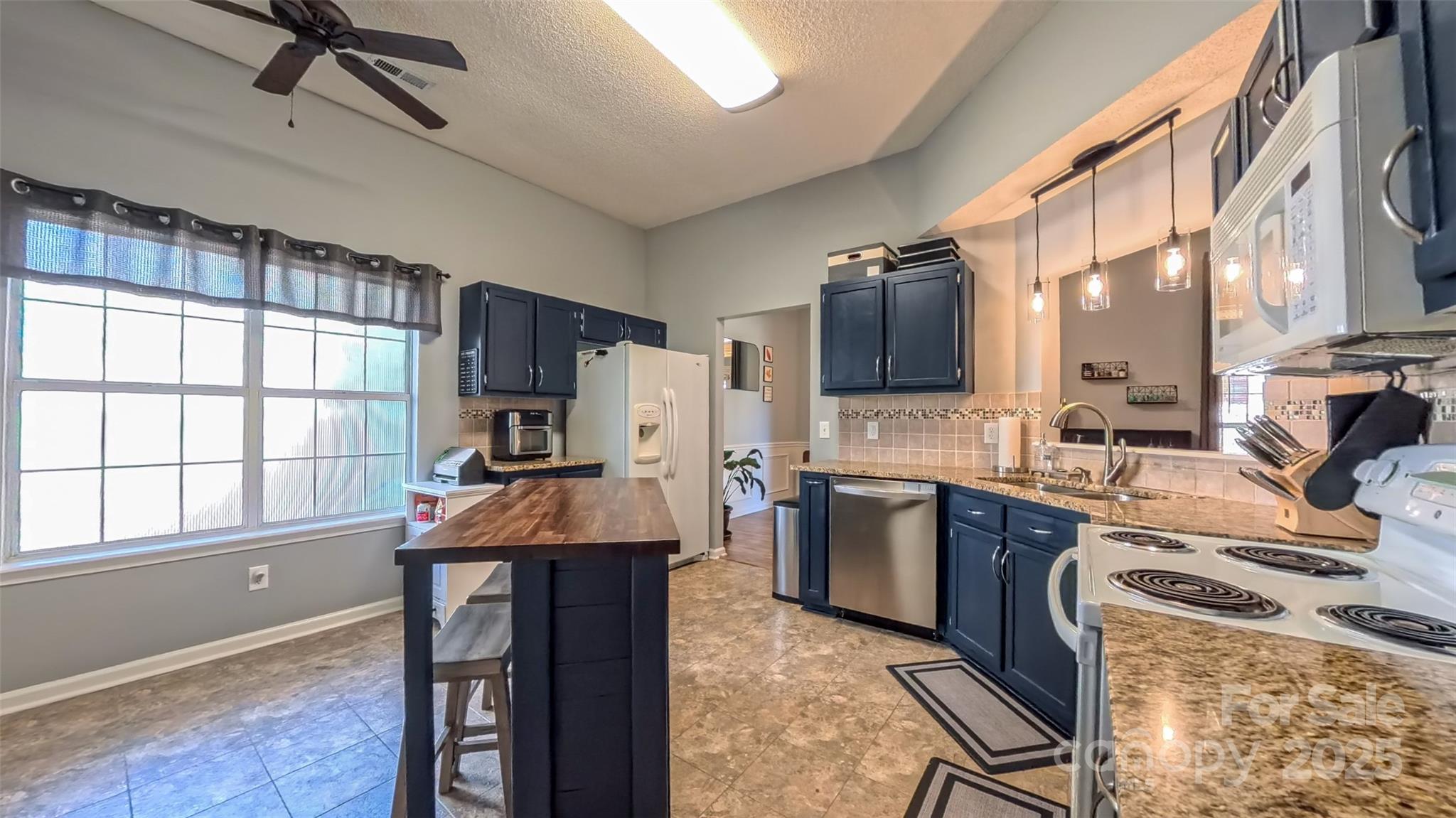 3693 Stonefield Street Southwest Concord, NC 28027 - Photo 16 of 27 a kitchen with stainless steel appliances kitchen island granite countertop a table chairs in it and wooden floors