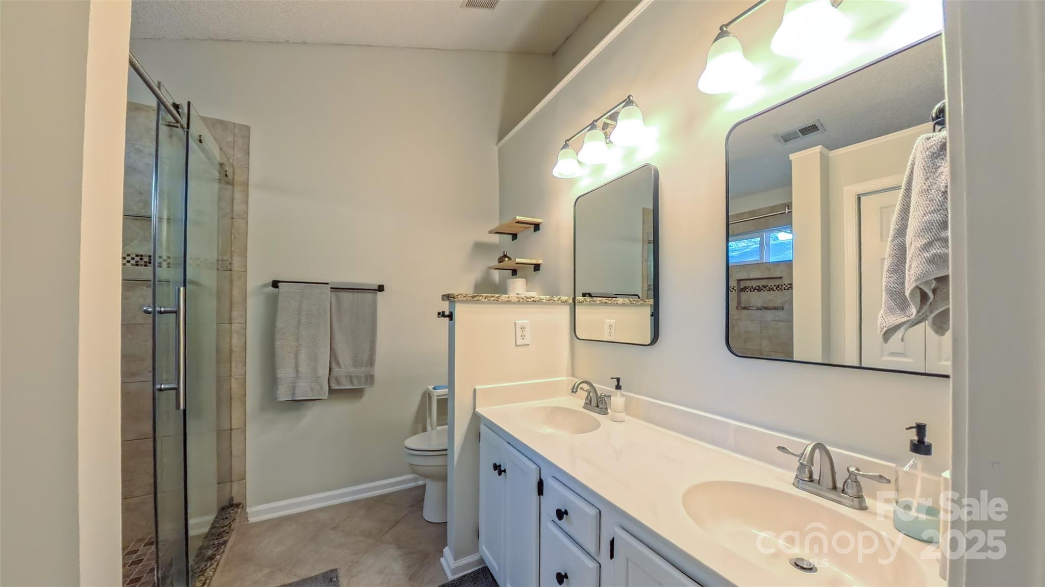3693 Stonefield Street Southwest Concord, NC 28027 - Photo 10 of 27 a bathroom with a granite countertop double vanity sink mirror and shower