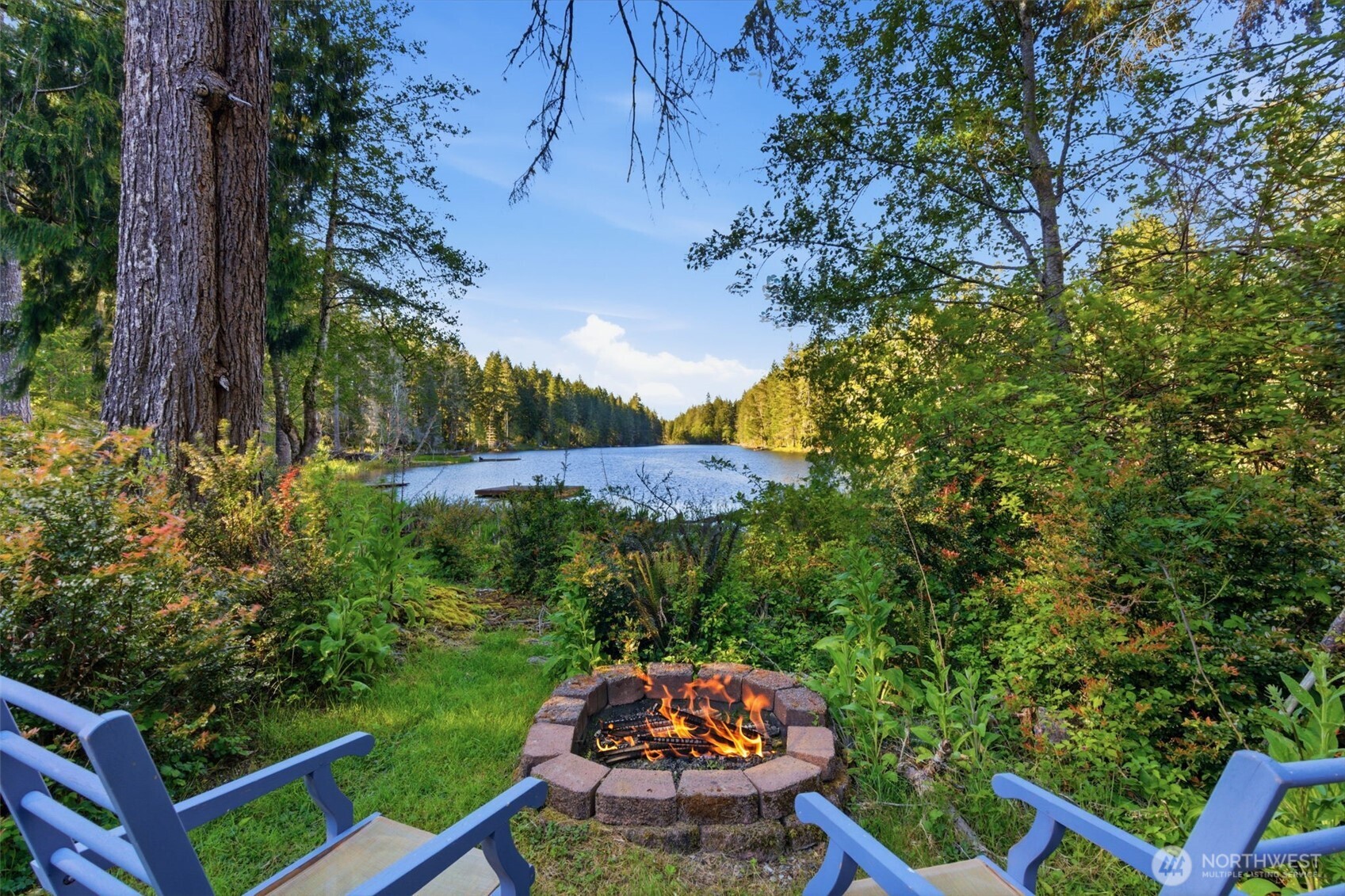 6971 Northeast Tahuya Blacksmith Road Belfair, WA 98528 - Photo 3 of 38 a back yard of the house with a table and chairs under an umbrella