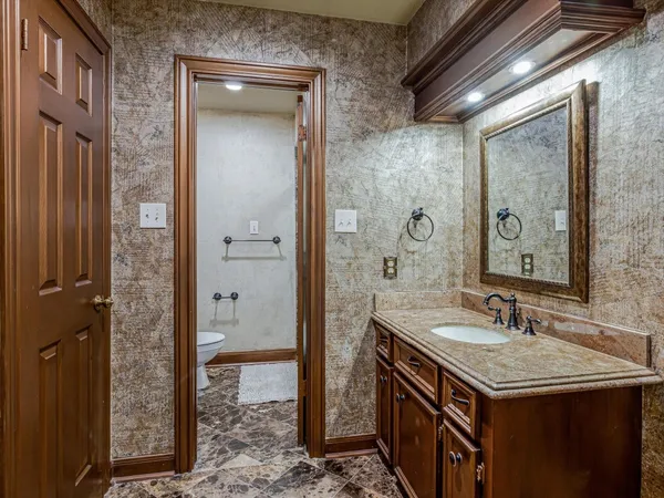 a bathroom with a granite countertop toilet sink and mirror
