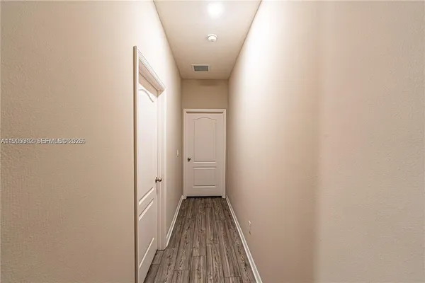 a view of a hallway with wooden floor and a bathroom