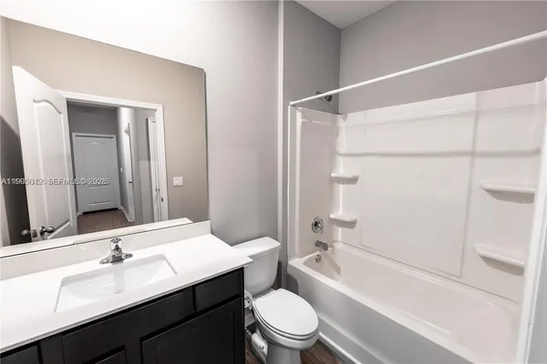 a bathroom with a sink a toilet a mirror a vanity and shower