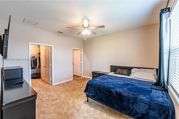 a bedroom with a large bed a flat tv screen and a dresser
