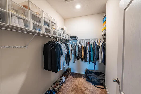 a view of walk in closet with clothes and shoes