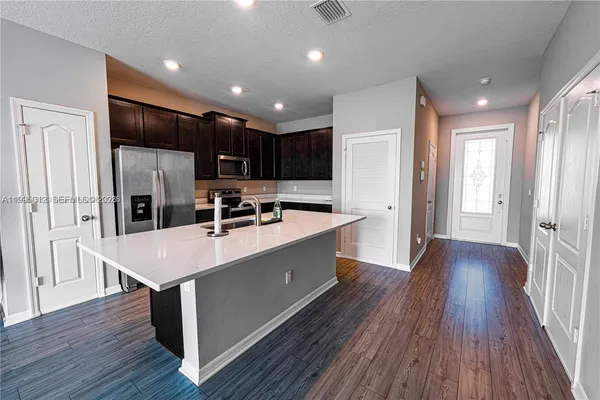 a kitchen with stainless steel appliances a refrigerator a sink dishwasher a oven and a microwave with wooden floor