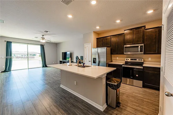 a kitchen with kitchen island stainless steel appliances a sink stove refrigerator and cabinets