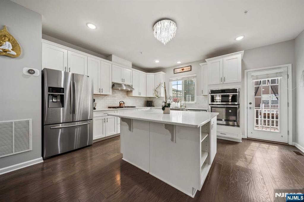 129 Truman Drive Wood-Ridge, NJ 07075 - Photo 16 of 47 a kitchen with stainless steel appliances granite countertop a refrigerator a stove oven a sink dishwasher and white cabinets with wooden floor