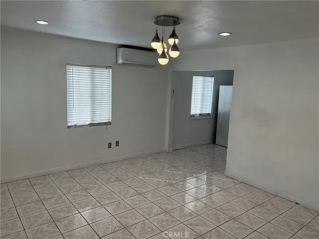 an empty room that has a chandelier fan and a window