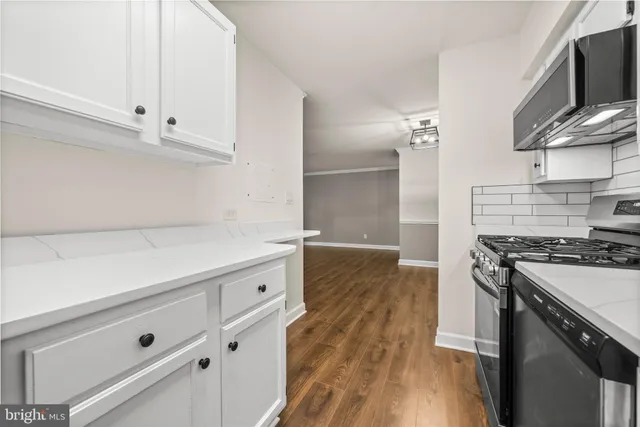 a kitchen with stainless steel appliances white cabinets and a wooden floor
