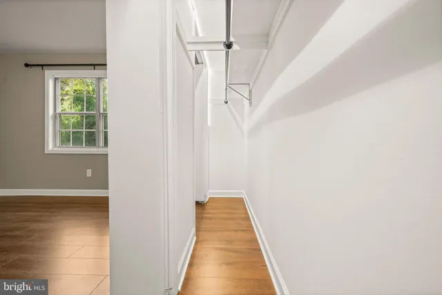 a view of a hallway with white walls and a window