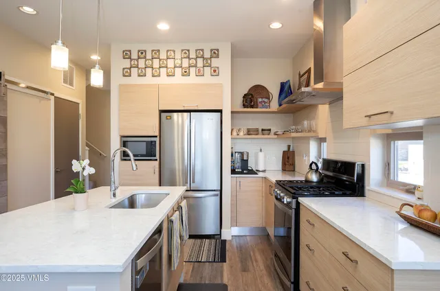 a kitchen with stainless steel appliances granite countertop a refrigerator a stove a sink dishwasher and white cabinets with wooden floor