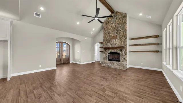 an empty room with wooden floor fireplace and windows