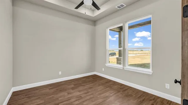 an empty room with wooden floor and windows