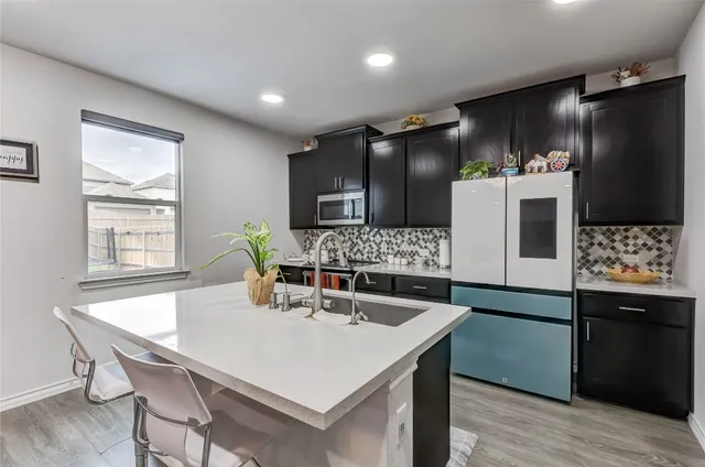 a kitchen with stainless steel appliances kitchen island granite countertop a table chairs and a refrigerator