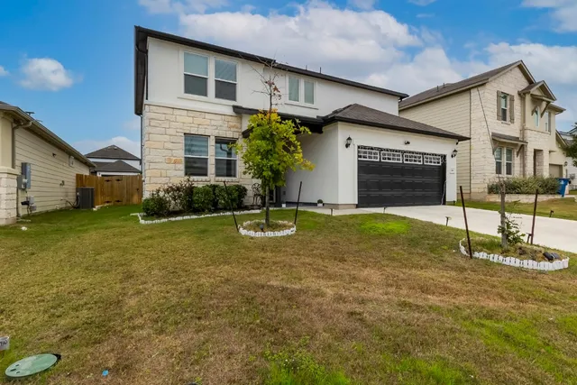 a view of yellow house with a yard and potted plants