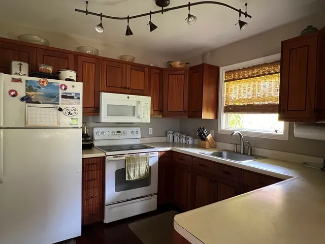 a kitchen with stainless steel appliances granite countertop a sink a stove a refrigerator cabinets and a window